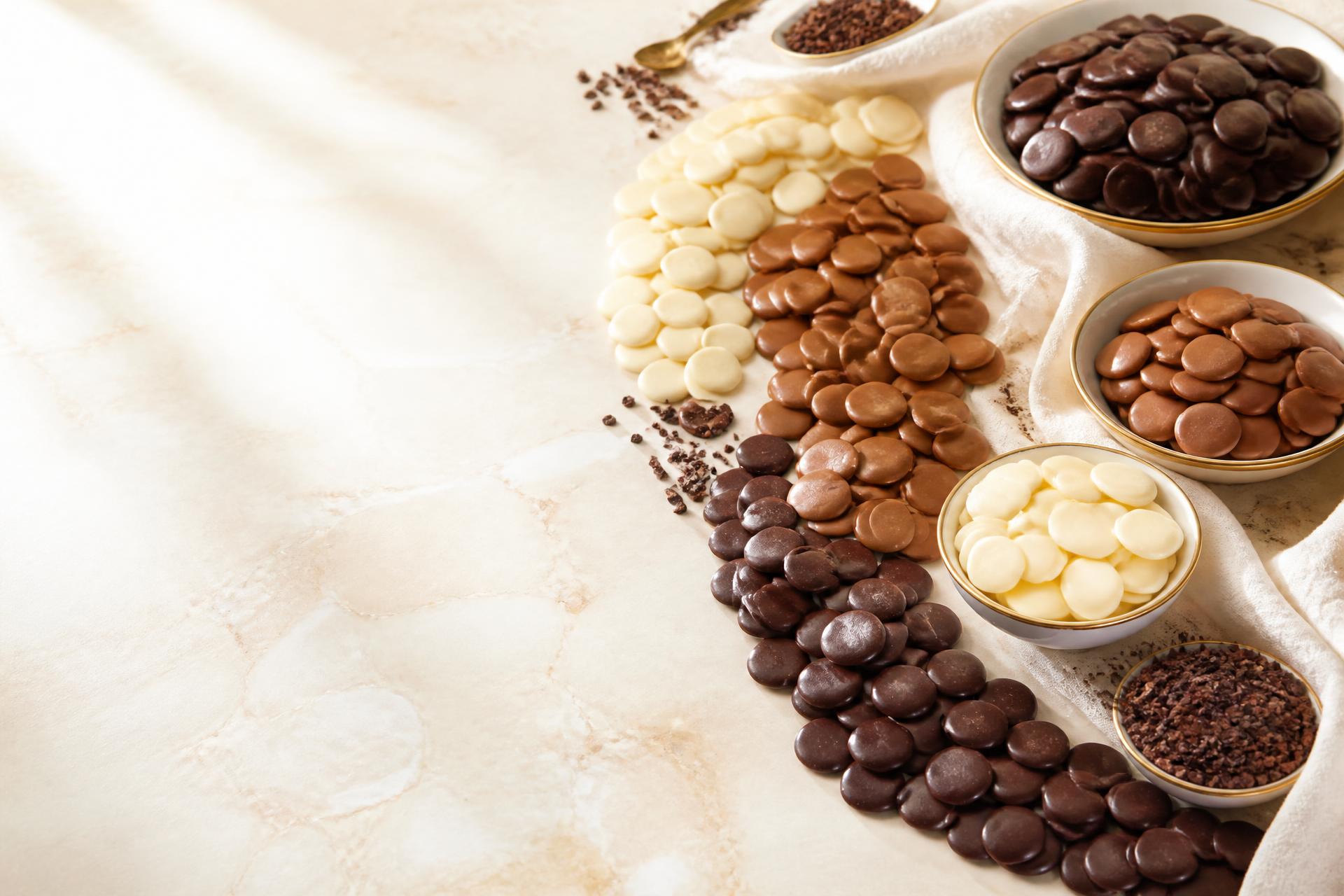 Dark, milk and white chocolate coins arranged on ivory marble